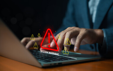 Businessman using laptop with digital system warning alert, representing cybersecurity risk,...