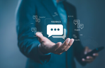 Businessman holding digital feedback icon with multilingual communication symbols, representing...