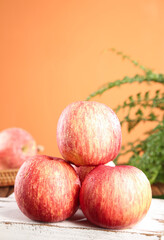 Fresh Red Fuji Apples Stacked on Rustic Wooden Table with Warm Orange Background
