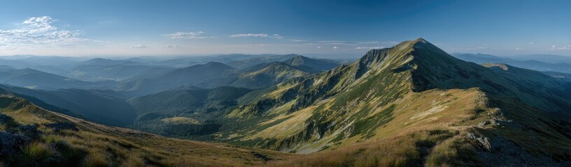 Obraz premium Panoramic mountain vista, showing a rugged mountain range with valleys and ridges, under a partly cloudy, clear blue sky