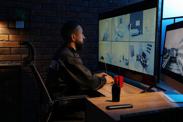Security guard monitoring CCTV cameras in office at night