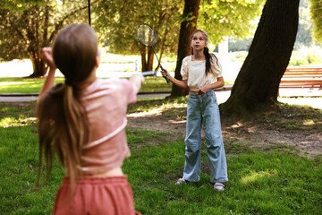 Cute little girls playing badminton in park, selective focus