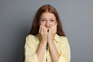 Teenage girl suffering from panic attack on grey background