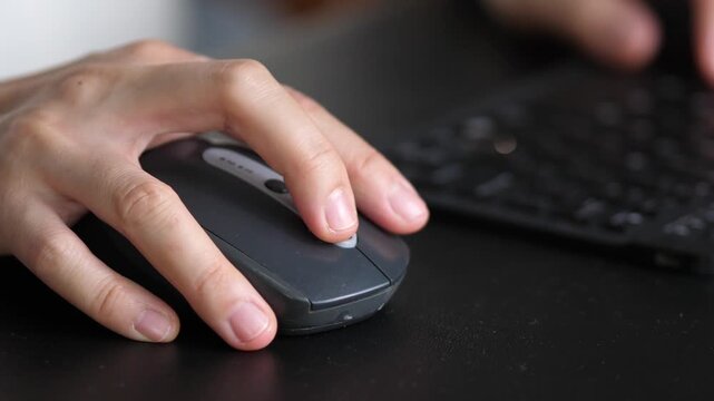 Close-up of hand using computer mouse while working at desk