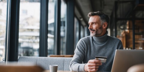 The thoughtful man enjoying coffee and using a laptop in a cafe.
