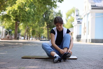 Teenage girl putting on tap shoes outdoors