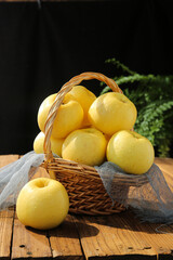 Fresh Golden Fuji Apples in Wicker Basket on Rustic Wood Table