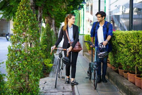 Asian man and woman walking with bicycles in the city on their way to work.
