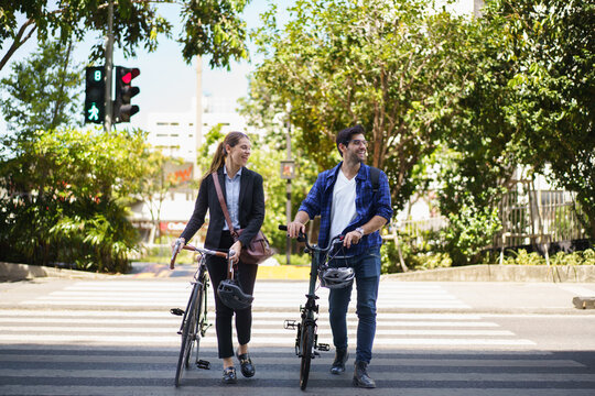 Asian man and woman walking with bicycles in the city on their way to work. - Powered by Adobe