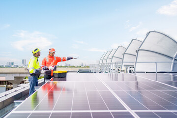 Engineers in safety gear inspecting solar panel installation on office building rooftop. Renewable...