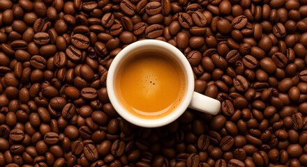 Fototapeta premium Top-down shot of glossy Arabica beans with espresso cup and rich crema