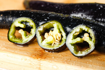 Fresh Purple Peppers Sliced with Water Droplets on Wooden Cutting Board