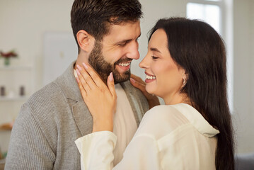 Portrait of a young couple in love looking at each other with tenderness standing at home. Happy...
