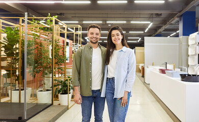 Portrait of a happy young family couple, clients, looking at camera in a plumbing shop. This image...