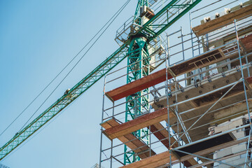 Construction site with crane and scaffolding under clear blue sky in urban area