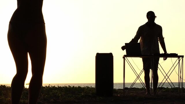 Woman dancing at sunset by the sea to DJ music
