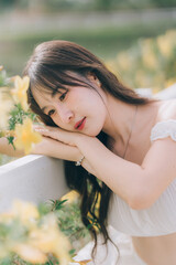 Serene Portrait in Nature's Embrace: A young woman with flowing hair leans gently on a surface...