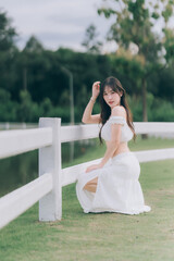 Grace and Serenity: A beautiful woman in a flowing white dress is captured in a serene outdoor...
