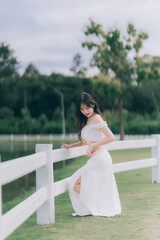 Elegant Posed Portrait: A stylish woman in a pristine white outfit poses gracefully, her form...
