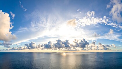 A vast expanse of serene ocean meets a vibrant sky filled with fluffy clouds, bathed in the soft glow of the setting sun.