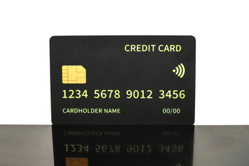 Macro shot of a contactless black credit card on a reflective surface against a white background
