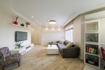 modern living room with a brown sectional sofa, textured wall, light wood floors, and stylish decor. A cozy, contemporary space