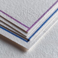 Close-up of textured paper sheets, stacked and showing colored borders