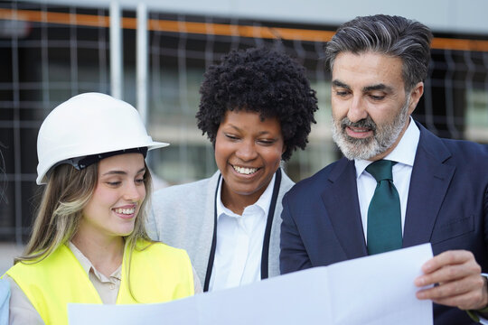 Architect, engineer and investor discussing building project using blueprint
