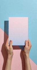 Hands holding a blank light-pink rectangle against a pastel pink and light blue backdrop