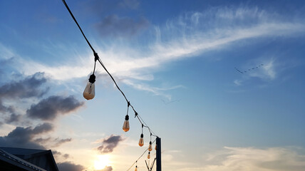 Outdoor hanging lights with clouds and evening sky in the background