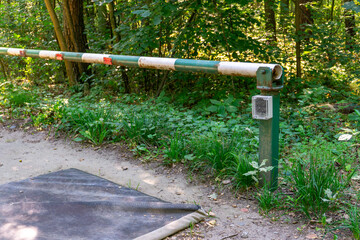 Fototapeta premium Forest road closed with a white and green barrier, disinfection mat at the entrance, element of sanitary protection and access control in woodland area.