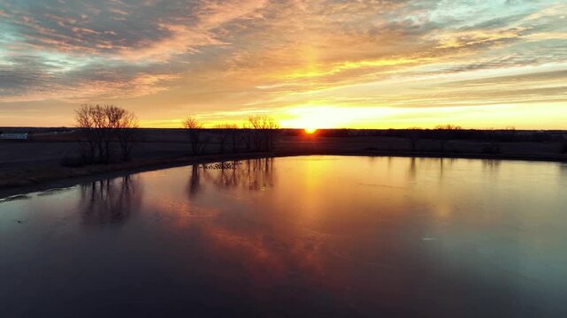 Aerial drone view of lake with ducks, trees, and fields in Oregon USA at sunset