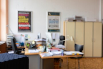 Blurred office interior with desk chairs posters and cabinets in a workspace area