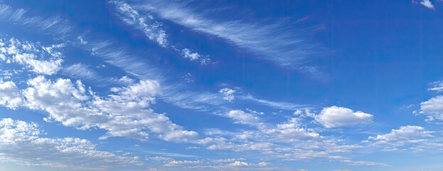 A vast expanse of a clear blue sky dotted with fluffy white clouds