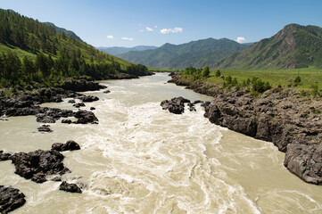 A stormy mountain river is muddy from clay washed down from the mountains.