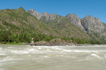 A stormy mountain river is muddy from clay washed down from the mountains.