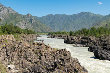 A stormy mountain river is muddy from clay washed down from the mountains.