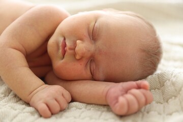 Cute newborn baby sleeping on bed indoors