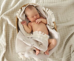Cute newborn child sleeping in baby nest on bed, top view