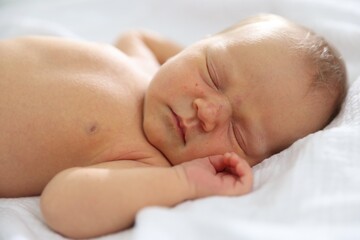 Cute newborn baby sleeping on bed indoors