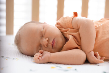 Cute newborn baby lying in crib indoors
