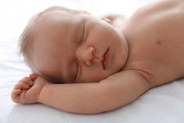 Cute newborn baby sleeping on bed indoors, closeup