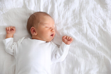 Cute newborn baby sleeping on bed, top view. Space for text