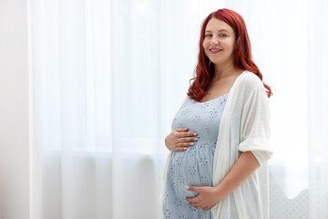 Beautiful pregnant woman at home, space for text