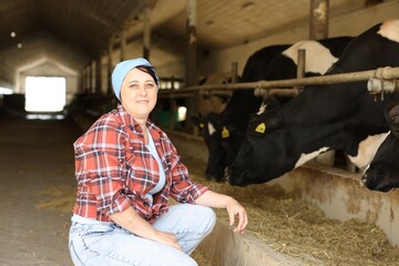 Portrait of farmer near cute cows inside cowshed in dairy farm