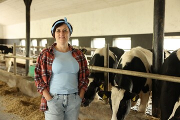 Portrait of farmer near cute cows inside cowshed in dairy farm