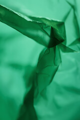 Extreme close up of green empty plastic bag background. The plastic surface is wrinkly and tattered...