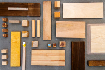 Flat lay of various wood and plywood pieces on concrete texture. Carpentry background.
