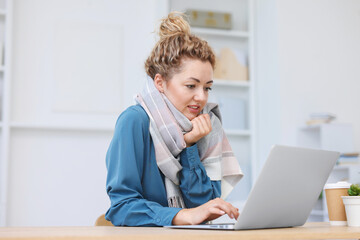 Air conditioning. Woman with scarf suffering from cold temperature at workplace in office