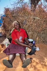 African woman eating porridge pap from a cauldron three legged pot, in a village in Botswana , in...